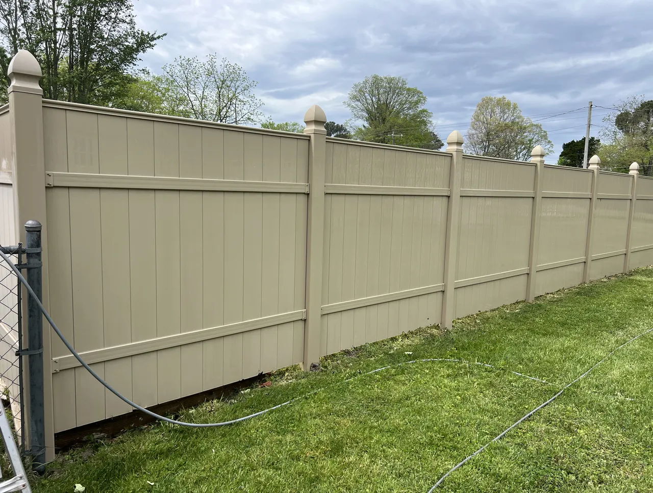 Long vinyl privacy fence washed clean along a back lawn