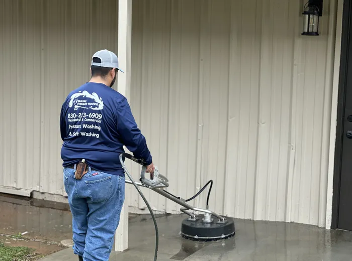 BlueJay cleaning concrete with a surface cleaner beside a metal building